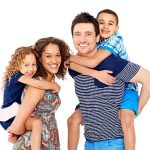 Portrait of playful young parents giving piggyback ride to children on white background
